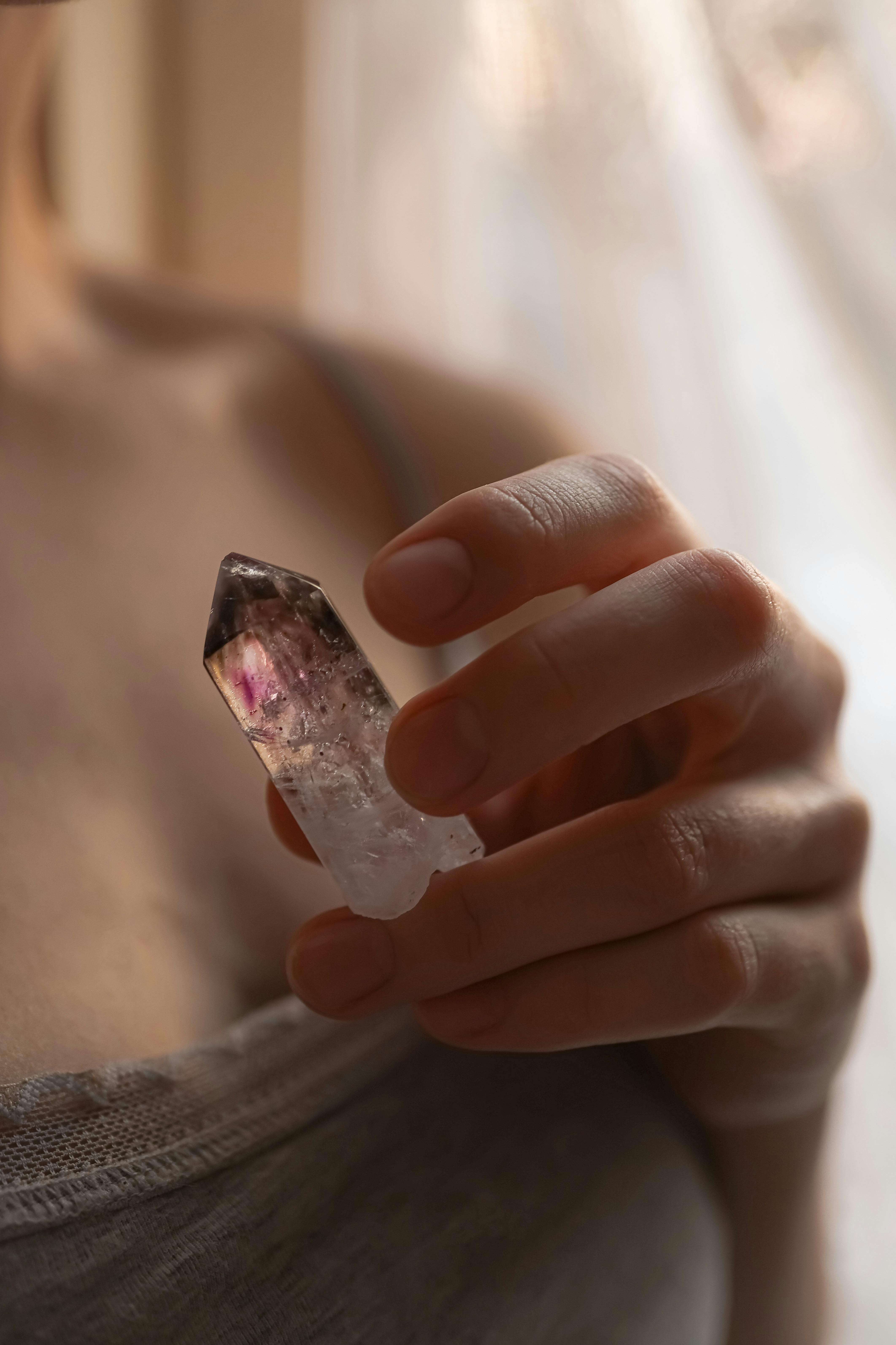 Direction 01 Presence — hand holding an amethyst crystal in soft warm window light