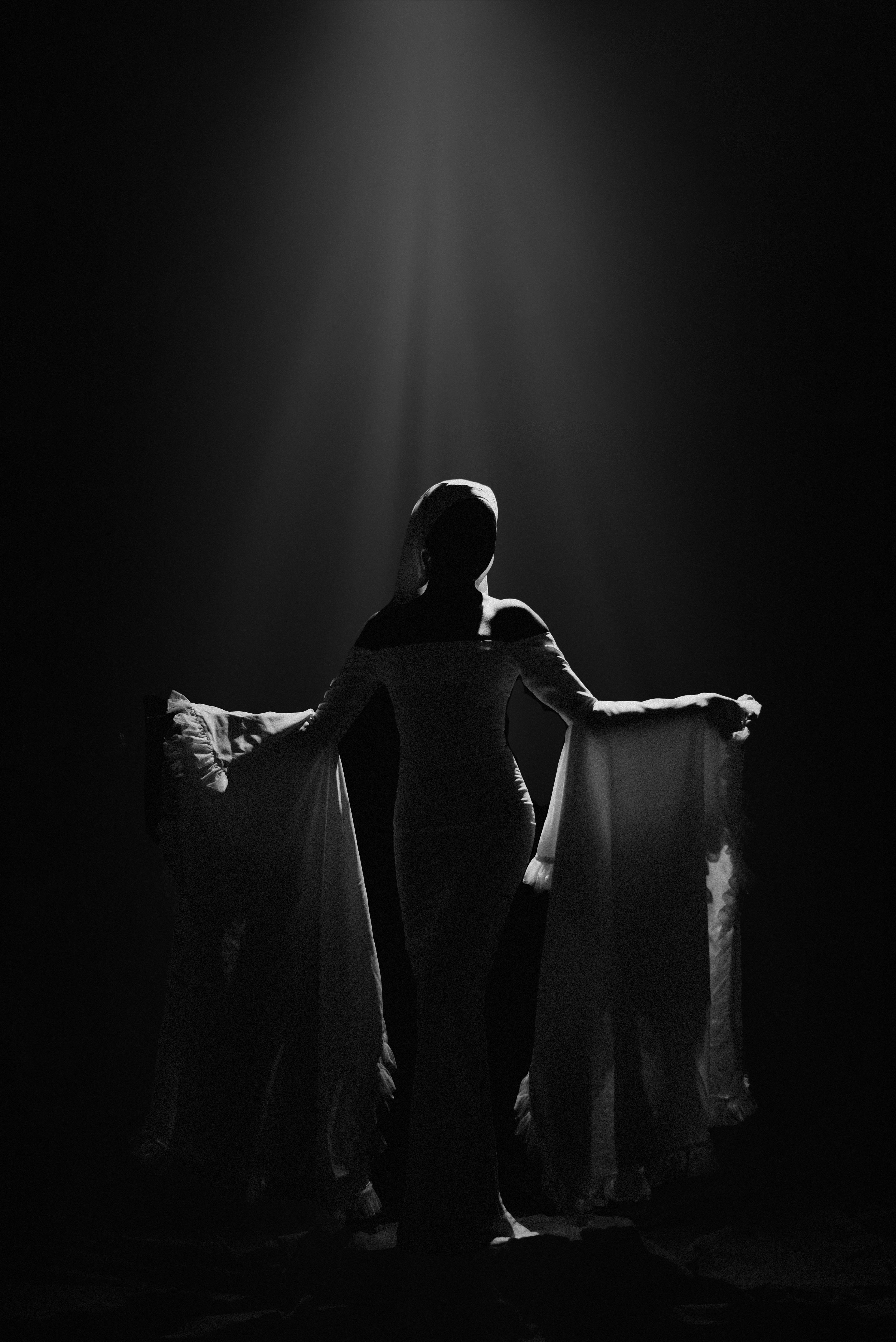 Direction 03 Presence — ethereal silhouette of a woman in a flowing dress under spotlight, luminous body in light